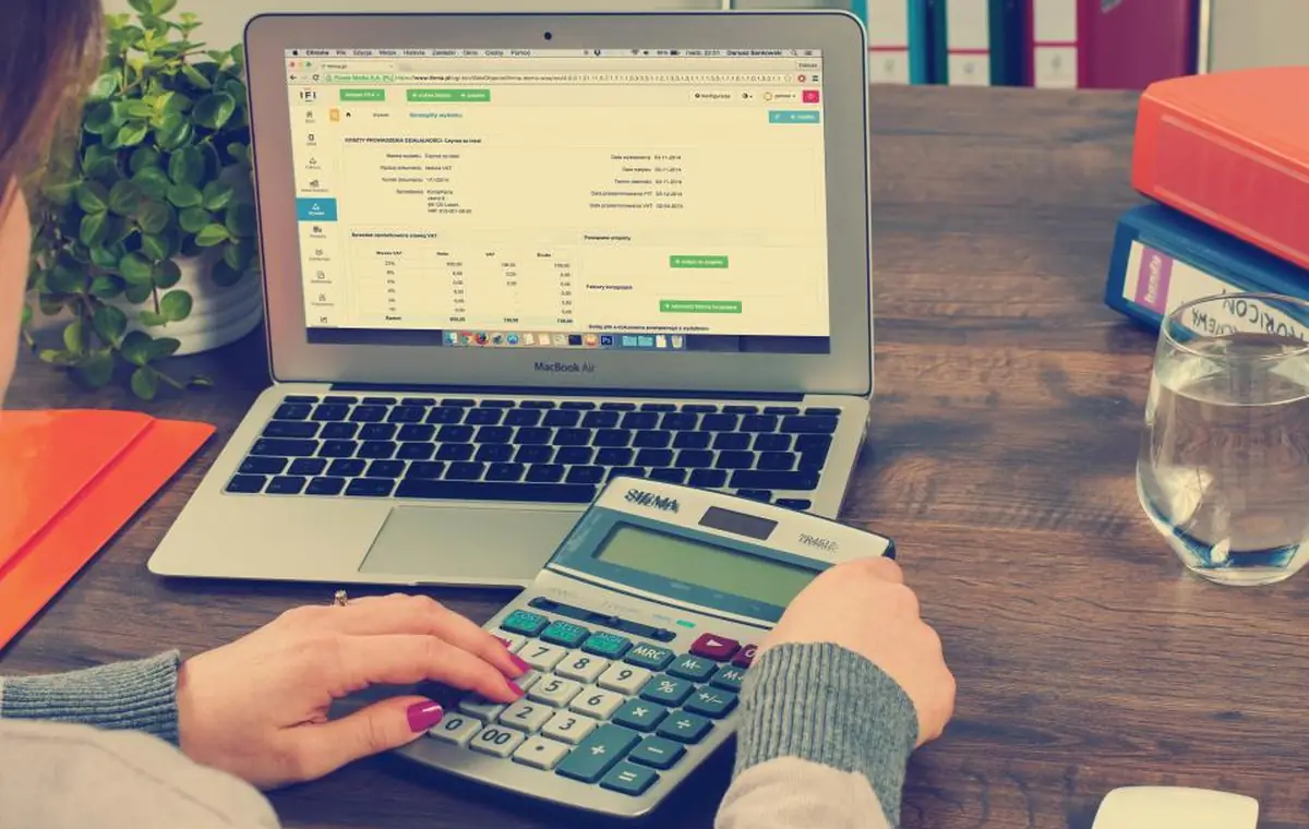 Calculatrice et documents financiers posés sur un bureau pour estimer un budget mensuel